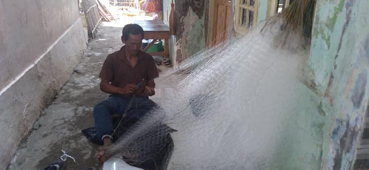 Rasja 65 tahun, nelayan di desa Patimban, duduk merajut jaring di lantai teras rumahnya usai pulang melaut yang hasil tangkapannya kurang dari 1 kg. (Foto: Suci Sekar/Tempo.co)