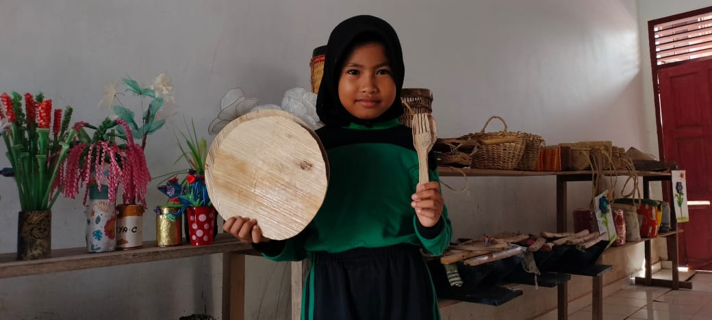 Siswi SD Negeri 67 Muara Sekalo menunjukkan piring dan garpu yang terbuat dari pelepah pinang. Pembuatan kerajinan ini menjadi kegiatan berbasis kearifan lokal. (Foto: Independen/M Sobar Alfahri)