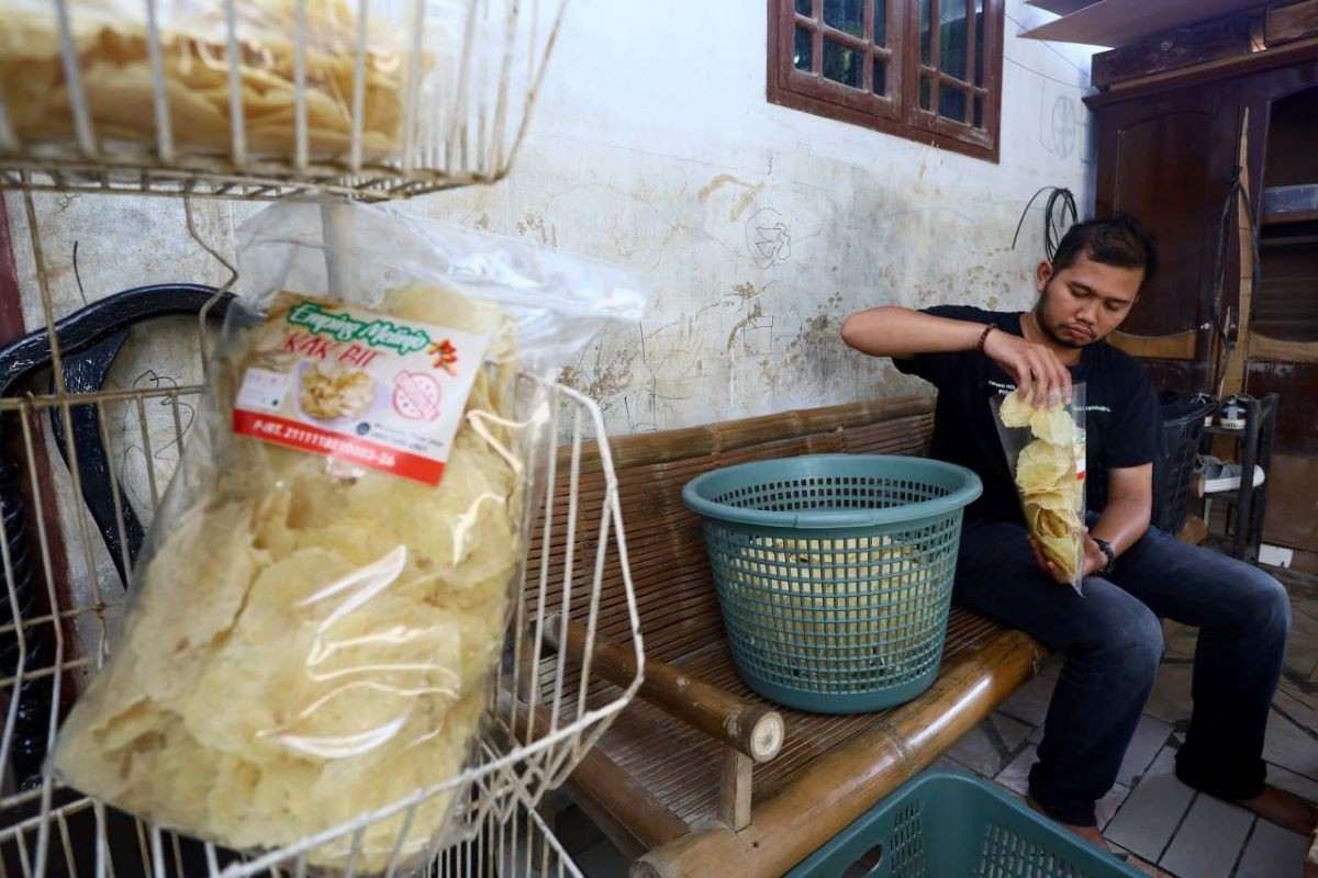 Khairul Mizan sedang memasukkan emping melinjo dalam kemasan di Desa Mesjid Tuha, Kecamatan Meureudu. (Foto: AJNN/Irfan Habibi) 